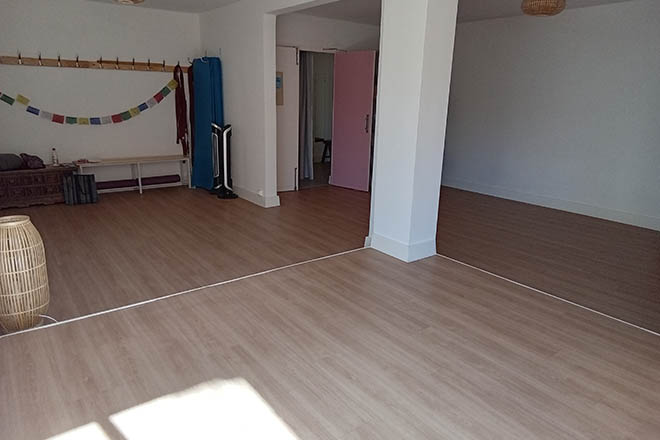 photo de la salle où se déroulent les cours et ateliers de Feldenkrais au cabinet kinés Guillaume Humet à Gap, la salle est claire, lumineuse et agréable dans les teintes de blanc, avec des touches de corail et bleu, avec un parquet clair au sol