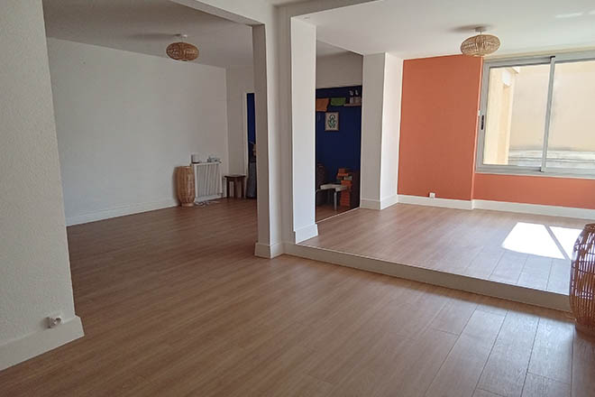 photo de la salle où se déroulent les cours et ateliers de Feldenkrais au cabinet kinés Guillaume Humet à Gap, la salle est claire et agréable dans les teintes de blanc, avec des touches de corail et bleu, avec un parquet au sol